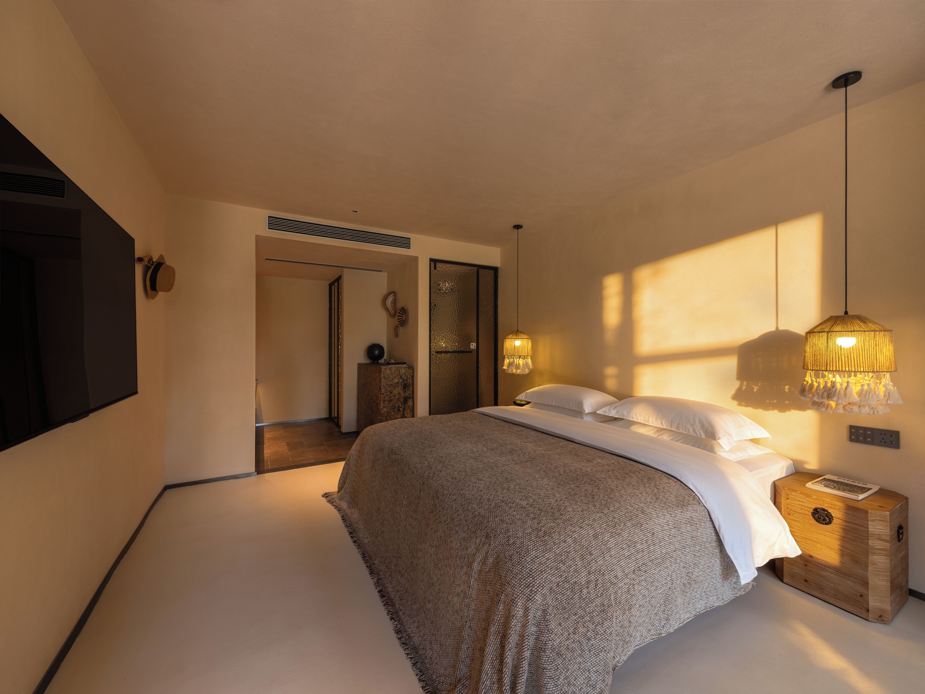 A modern bedroom with a large bed, bedside tables, a wardrobe, and a hanging light fixture.