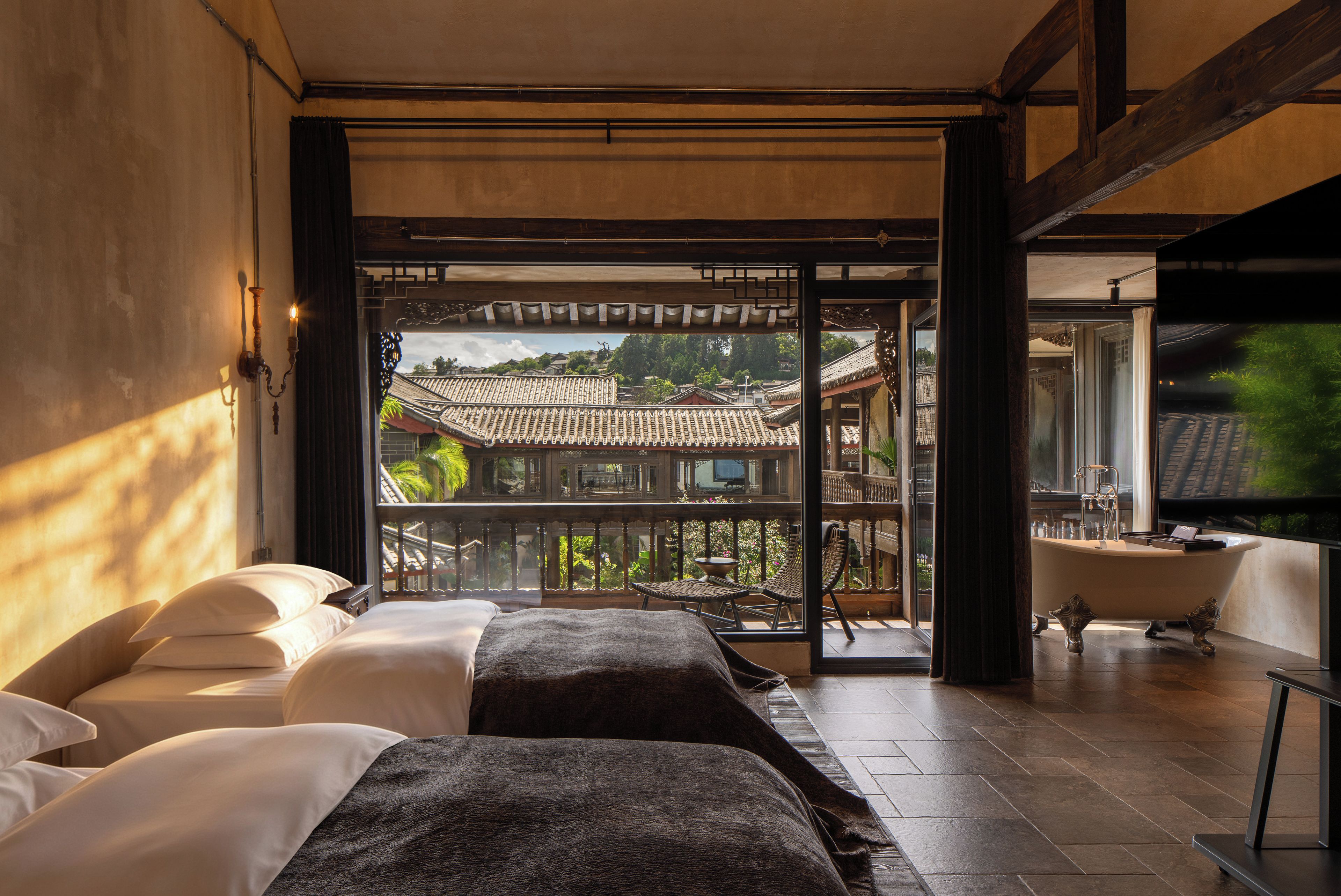 A hotel room with a balcony, a bathtub, and a bed.