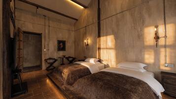 A hotel room with a large bed, a smaller bed, a desk, and a wardrobe.
