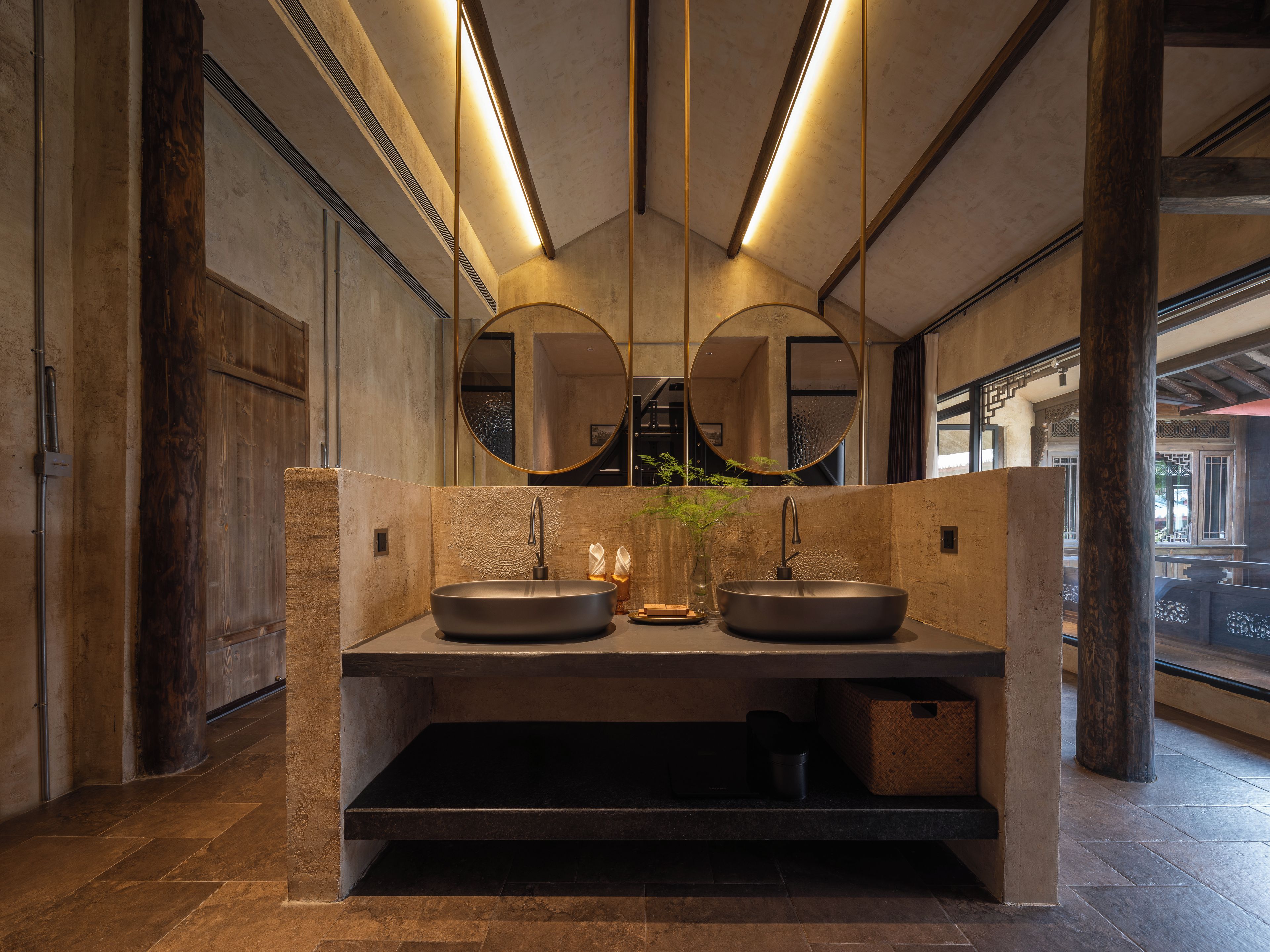 Une salle de bain moderne avec deux lavabos, un grand miroir et un vase avec une plante.