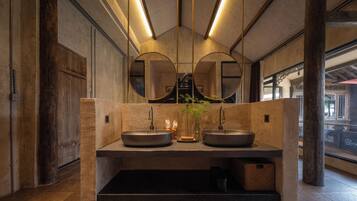 Une salle de bain moderne avec deux lavabos, un grand miroir et un vase avec une plante.