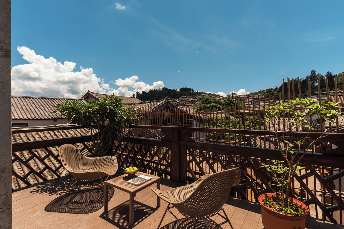 A terrace with wicker furniture, a table, and a potted plant.