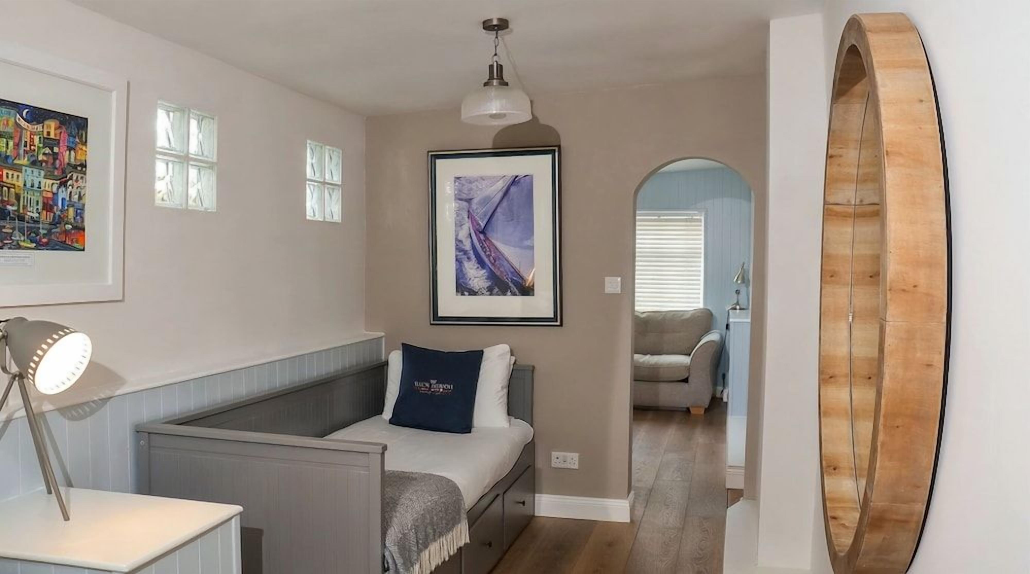 A bedroom with a bed, bedside table, lamp, and artwork on the wall.