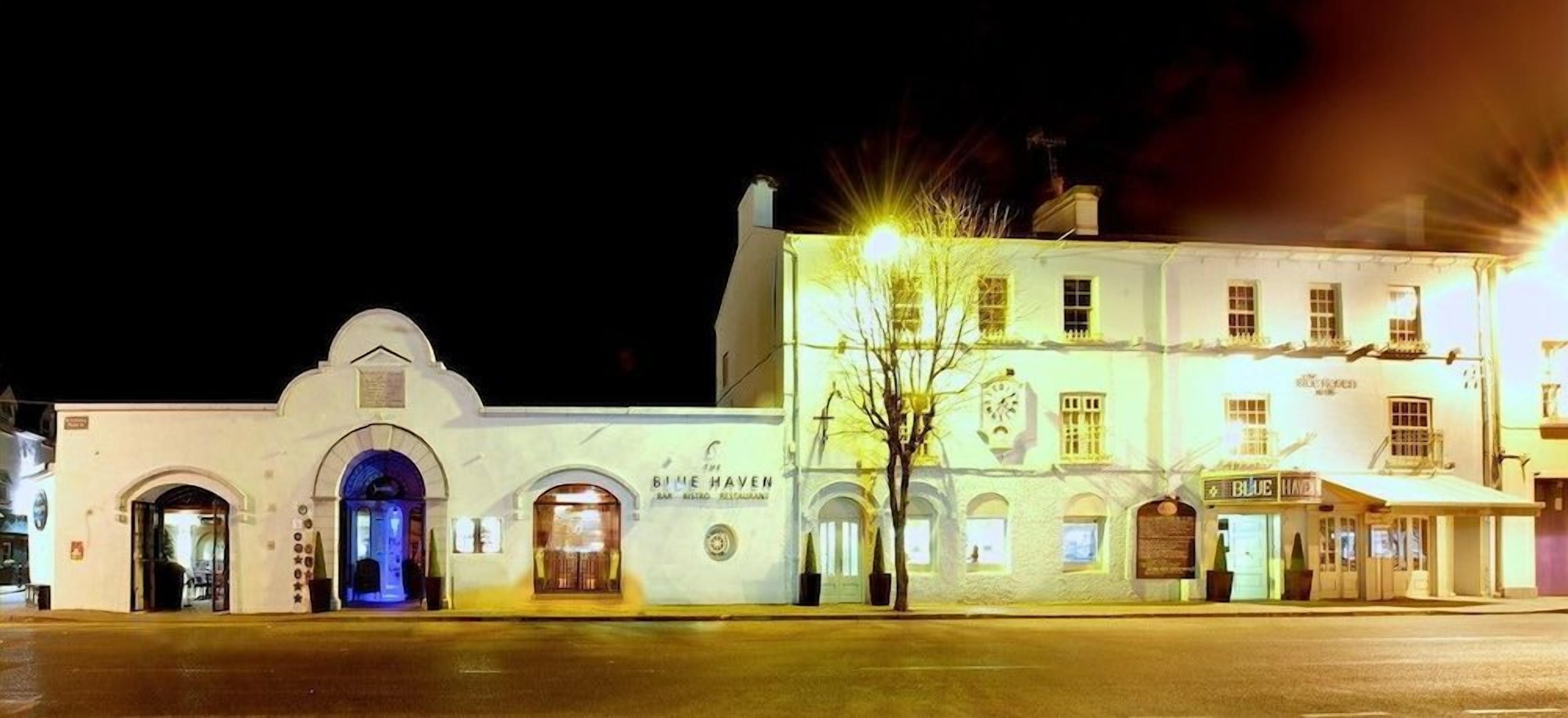 Un edificio histórico con varias puertas y ventanas, iluminado por luces de la calle.