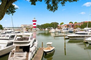 Ein Hafen mit mehreren vertäuten Booten, einem markanten Leuchtturm und Gebäuden im Hintergrund.