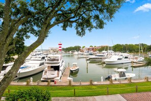 A marina with boats docked, a lighthouse in the background, and a grassy area in the foreground. - 1030 Caravel Court at The Sea Pines Resort (Hilton Head Island)
