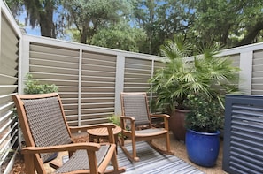 A patio with two wicker chairs, a small table, and a large potted plant. - 212 Twin Oaks at The Sea Pines Resort (Hilton Head Island)