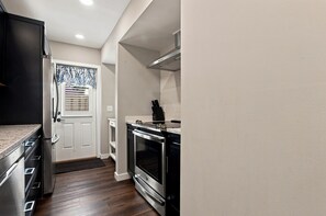 Eine kleine Küche mit integriertem Backofen, einem Kühlschrank und einem Fenster mit Jalousien.