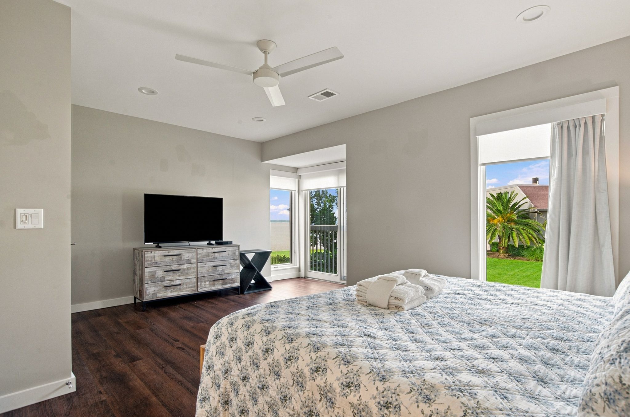 Une chambre à coucher avec un lit, une télévision, un ventilateur de plafond et une vue sur l’extérieur.