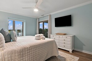 A bedroom with a bed, a dresser, a television, and a view of the outdoors. - 1811 Bluff Villas at The Sea Pines Resort (Hilton Head Island)