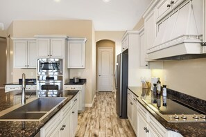 A modern kitchen with white cabinetry, stainless steel appliances, and a marble countertop. - YOUR ARIZONA HOME FOR THE MONTH! (Goodyear)