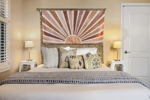 Ein Bett mit einer strukturierten Decke, ein Wandpaneel mit Sonnendesign und zwei Nachttischlampen.
