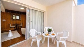 Un balcon avec une table à manger, des chaises et une petite plante en pot.
