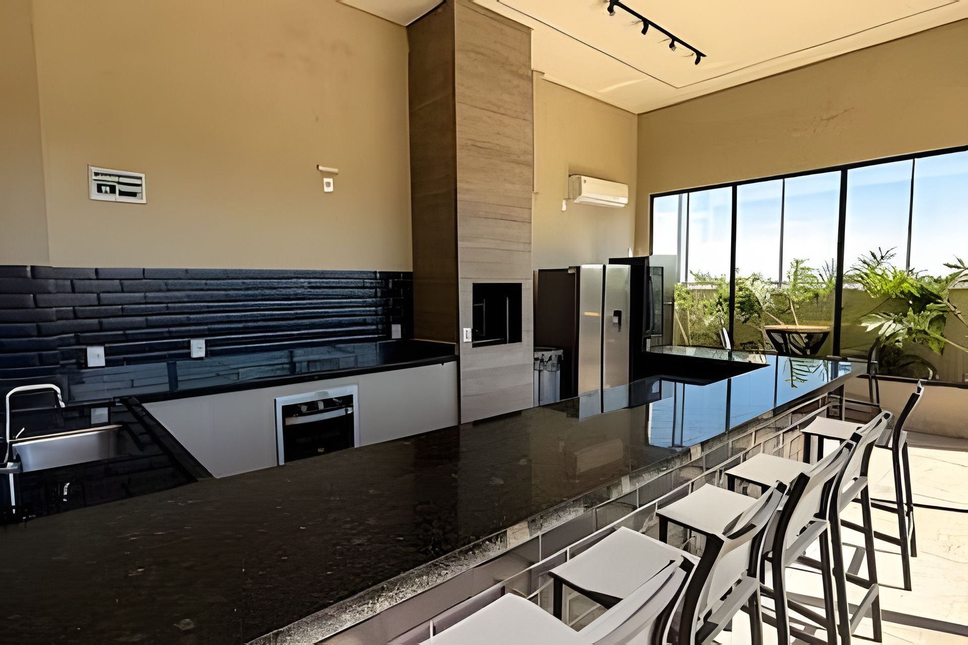 A modern kitchen with a black countertop, stainless steel appliances, and a large window offering a view of greenery.
