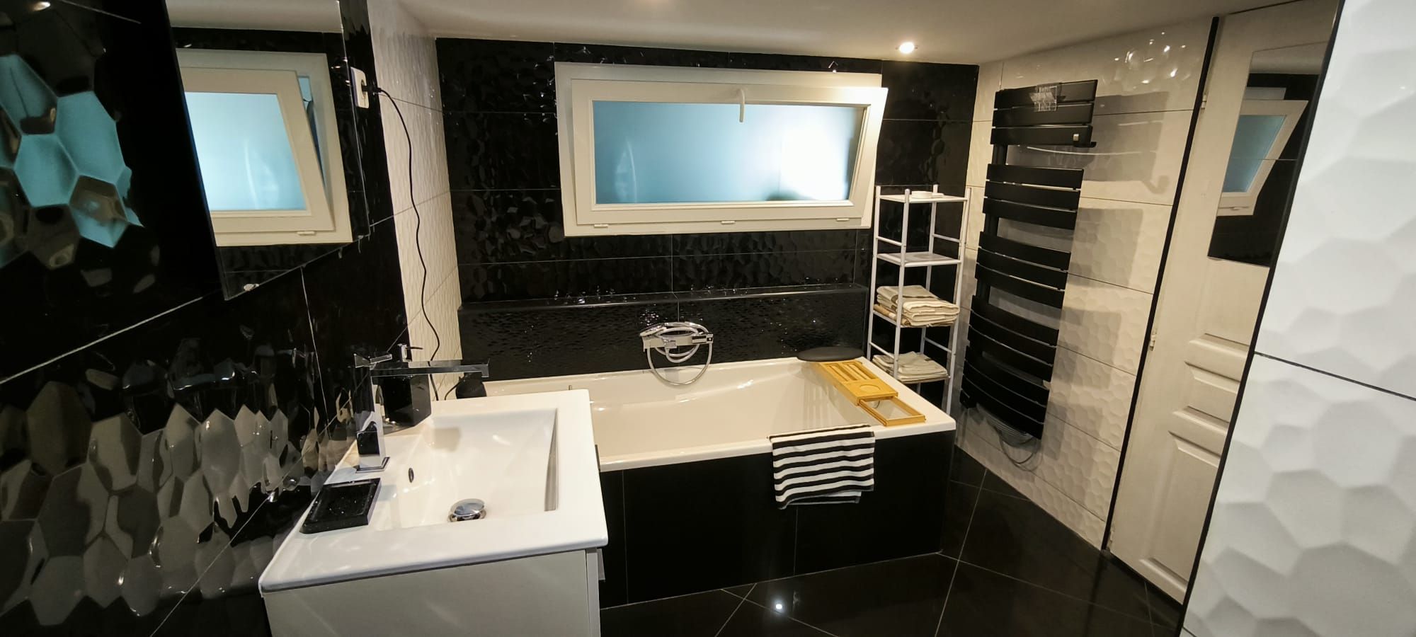 Un baño moderno con un lavamanos blanco, una bañera y una ventana sobre el espejo.