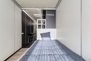 Ein schmaler Raum mit Bett, Schreibtisch und Stuhl.