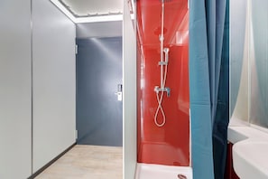 Ein modernes Badezimmer mit Duschkabine, Toilette und einer Tür zu einem anderen Raum.