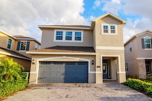 A two-story house with a garage, a small porch, and a well-maintained front yard. - 6BR Near Disney Pool, spa & 2 Game Rooms (Kissimmee)