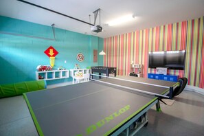 A room with a ping pong table, a dartboard, and a TV. - 6BR Near Disney Pool, spa & 2 Game Rooms (Kissimmee)