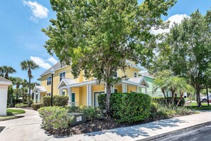 A two-story residential building with a yellow facade, white trim, and a covered porch. - 2BR Condo Near Disney Resort With Pool (Kissimmee)