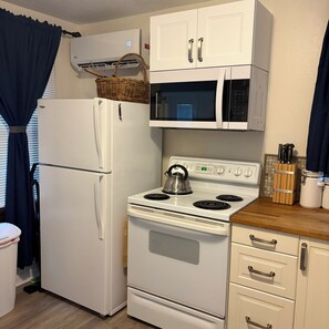 A compact kitchen with a refrigerator, microwave, stove, and wooden countertop. - Perfect & cozy 1-bedroom cottage on the ALAFIA RIVER  Riverview (Riverview)