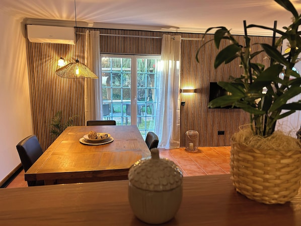 A dining area with a wooden table, chairs, a decorative bowl, a woven basket, and a potted plant.