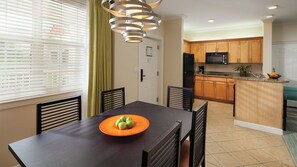 A dining area with a table, chairs, and a fruit bowl. There is a kitchen in the background with wooden cabinets and appliances. - Vacation of a Life time in Harbor-side Resort at Atlantis Paradise Island Nassau (Paradise Island)