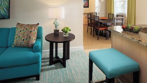 A living room with a teal sofa, a small round table with a lamp, and a bench. - Vacation of a Life time in Harbor-side Resort at Atlantis Paradise Island Nassau (Paradise Island)