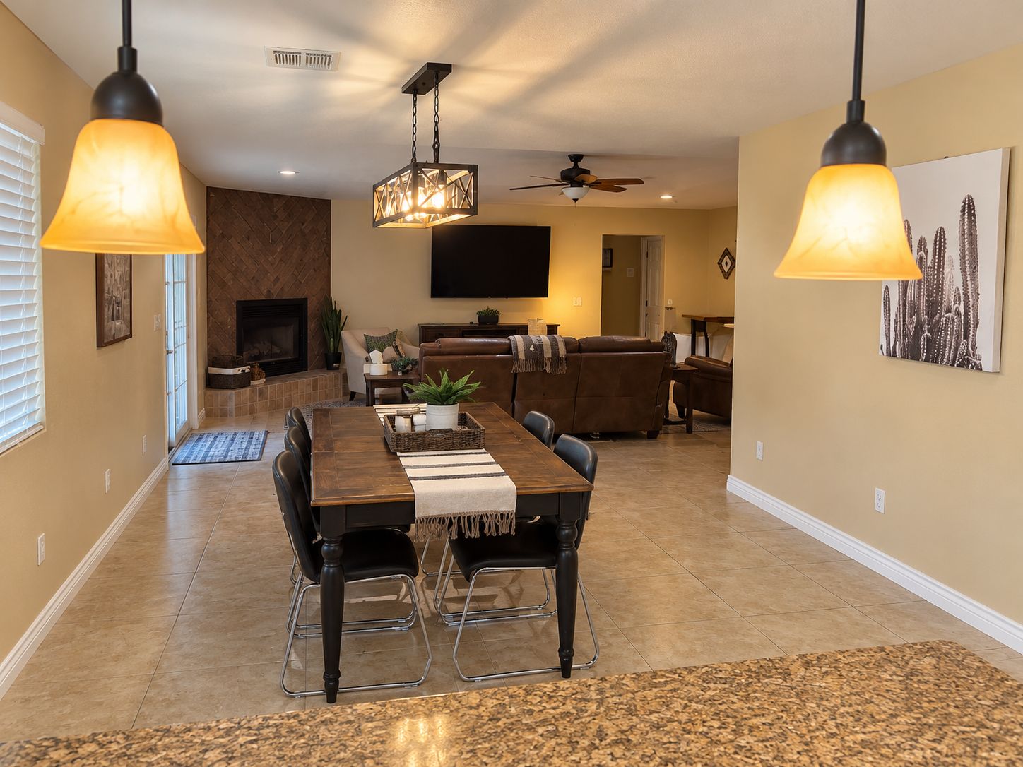 A dining area with a wooden table, chairs, and hanging pendant lights.
