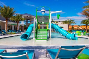 Ein Wasserpark mit Rutschen und Poolbereich, umgeben von Palmen und Liegestühlen.