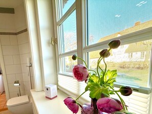 Ein Badezimmer mit Toilette, einem weißen Schrank und einem Fenster mit Blick auf ein Haus.