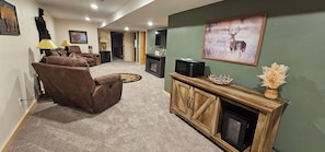 A living room with a brown leather sofa, a wooden entertainment center with a television, and a fireplace. - Up North Hideway 50 private acres  sleeps 10. 5 BR. ATV trail access (Emily)