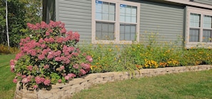 A house with a stone retaining wall and a variety of flowering plants. - Up North Hideway 50 private acres  sleeps 10. 5 BR. ATV trail access (Emily)