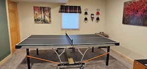 A ping pong table in a room with a window, wall decorations, and a door. - Up North Hideway 50 private acres  sleeps 10. 5 BR. ATV trail access (Emily)