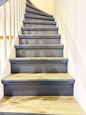 A staircase with dark steps and a wooden finish at the bottom. - Modern House for 10 Guests in Haan – 5 Bedrooms, Parking, and Self-Check-In (Haan)