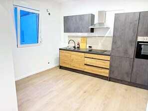 A modern kitchen with wooden cabinets, a stainless steel sink, and a built-in oven. - Modern House for 10 Guests in Haan – 5 Bedrooms, Parking, and Self-Check-In (Haan)