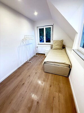 A small, well-lit room with a bed, a window, and a radiator. - Modern House for 10 Guests in Haan – 5 Bedrooms, Parking, and Self-Check-In (Haan)