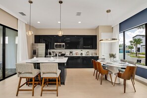A modern kitchen with black cabinets, stainless steel appliances, and a central island with seating. - 5BR Near Disney Private Pool & Lake View (Davenport)