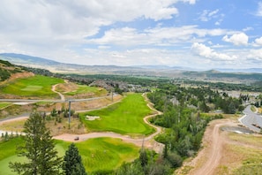 A golf course with a clear view of the surrounding landscape, including distant hills and a small town. - 1 Bedroom Condo w/ Ski-in/out Access + Fireplace (Park City)