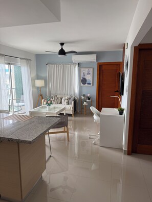 A modern living space with a kitchen area, dining table, sofa, and a ceiling fan. - 2-bedroom apartment in marvelous Punta Cana with cool AC (Punta Cana)