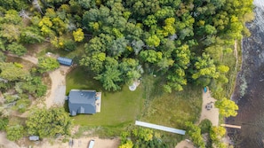 An aerial view of a property with a large house, a covered outdoor area, and a beach area with a wooden walkway. - Pelican Lake Getaway, 2BR + Office, Beach & Pedal Boat (Breezy Point)