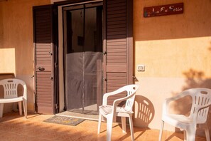 A closed door with a metal handle, two white plastic chairs, and a welcome mat with 'HELLO' and 'WELCOME' on a tiled floor. - La Ca'Setta (La Maddalena)
