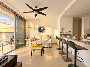 A modern living room with a balcony overlooking the sea, a ceiling fan, and a dining area with bar stools. - MorrosCity / Luxurious Beach Vacation & Ocean View   (Cartagena de Indias)