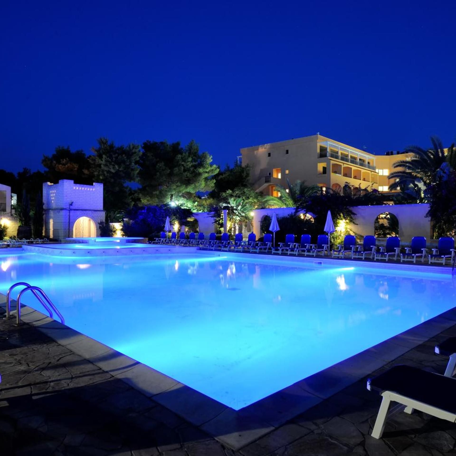 A swimming pool with lounge chairs and a building in the background.