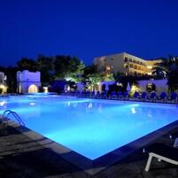 Una piscina con lettini e un edificio sullo sfondo.