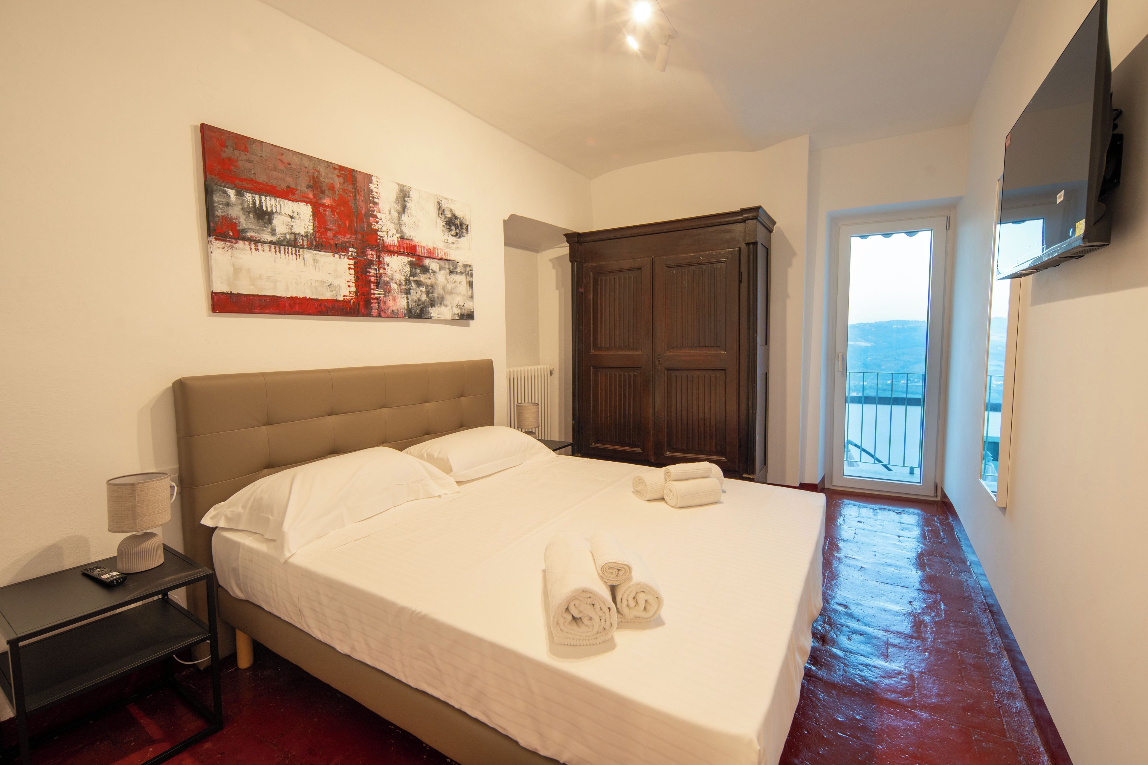 Una camera d'albergo con un letto grande, un quadro appeso al muro, un armadio e un televisore montato a parete.