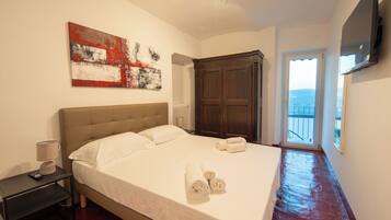 Una camera d'albergo con un letto grande, un quadro appeso al muro, un armadio e un televisore montato a parete.