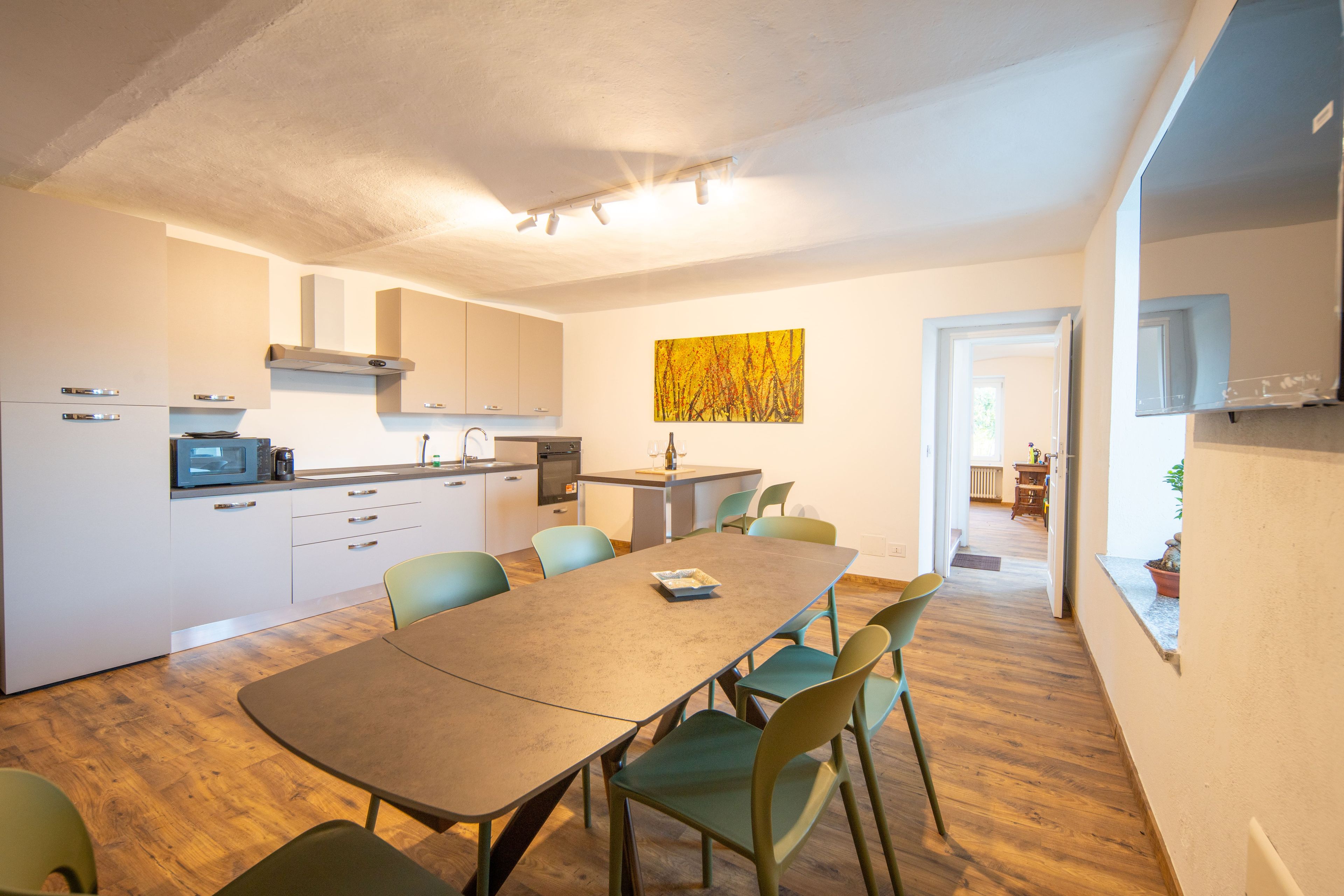 A modern kitchen with built-in appliances, a dining area with a table and chairs, and a view into the living room.