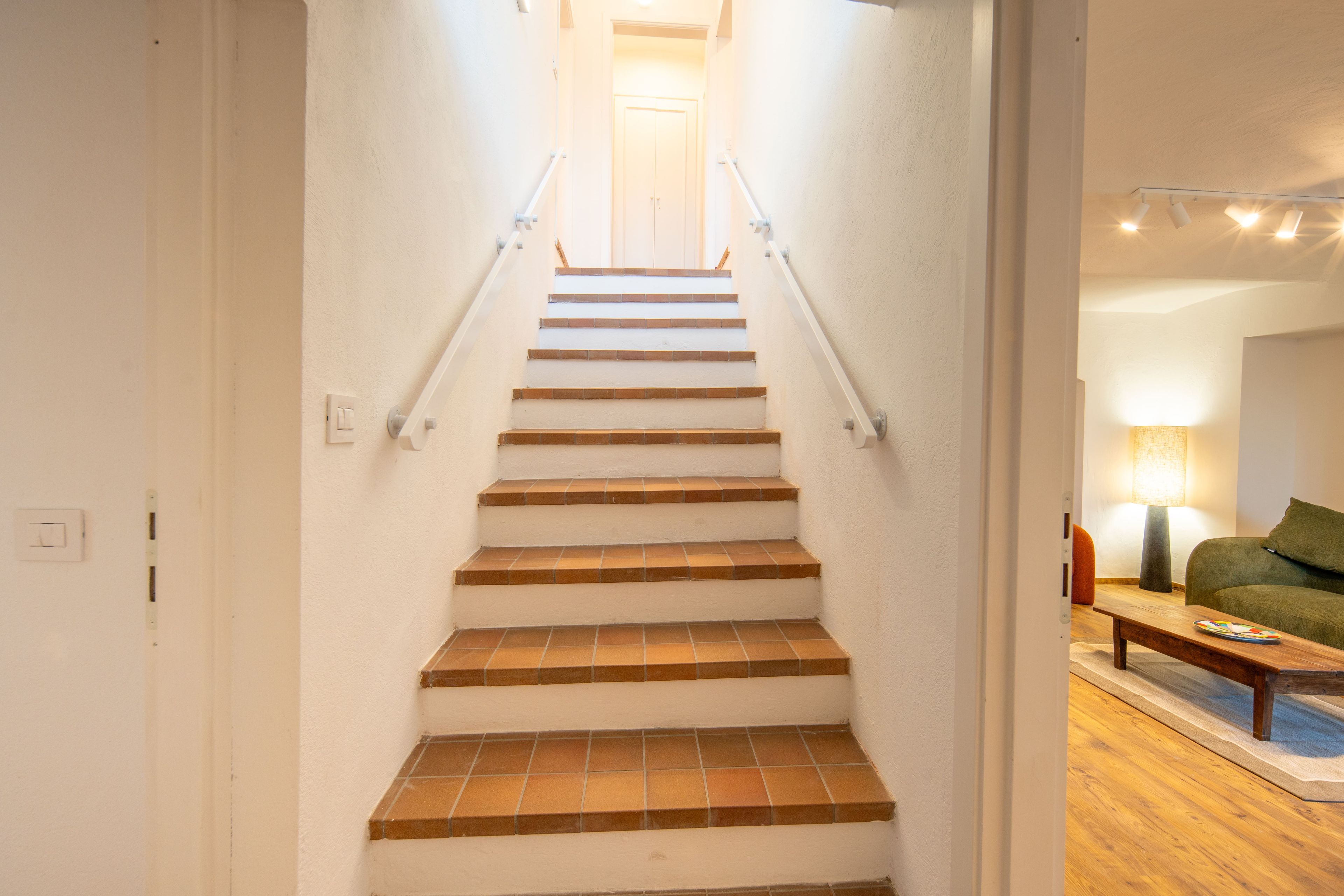 Un escalier muni d’une rampe, menant à une porte située en haut.
