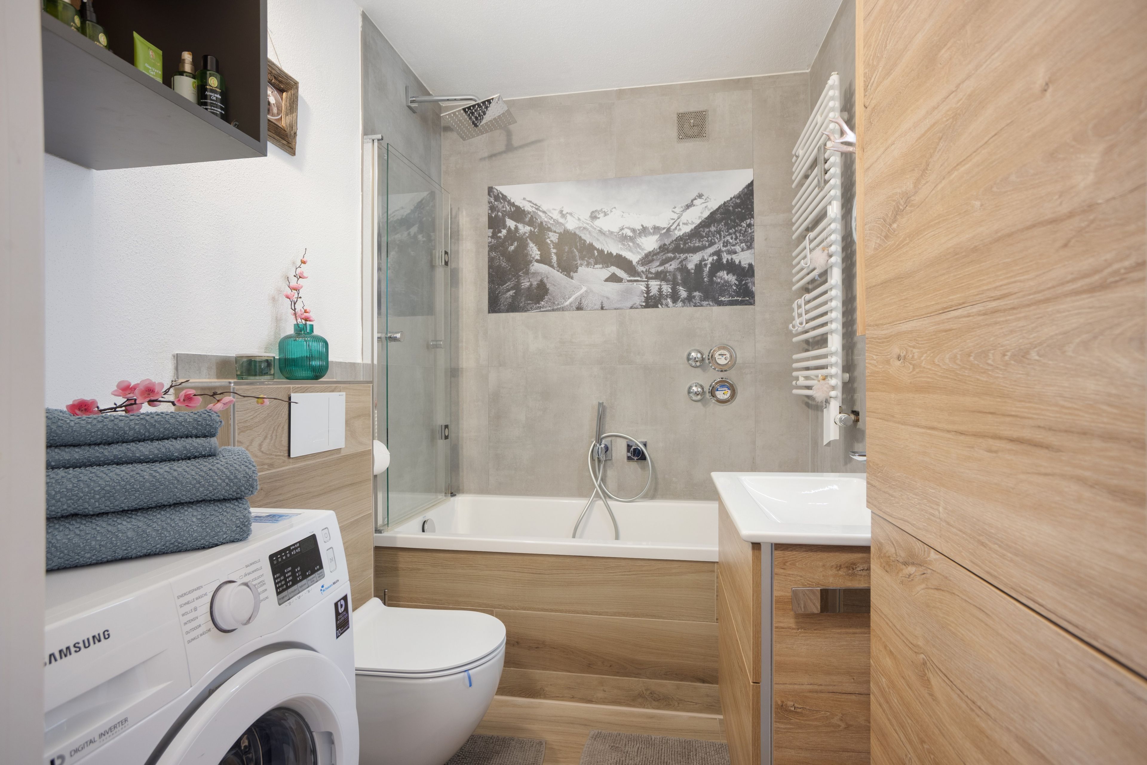 Ein modernes Badezimmer mit Waschmaschine, Toilette, Badewanne und Dusche.